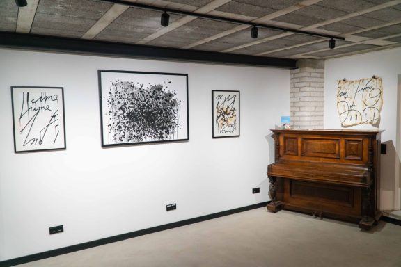 Ein Piano steht vor einer Wand mit vier gerahmten Kunstwerken.