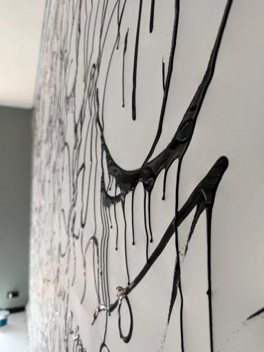 Wand mit schwarzen, tropfenden Linien und abstraktem Muster auf hellem Hintergrund.